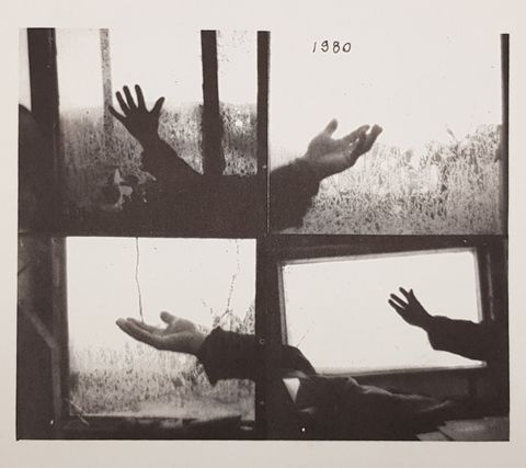 Book cover. Four black and white photographs show four hands reaching out towards or through windows, as if feeling for rain. The top right image has the date written above the hand.